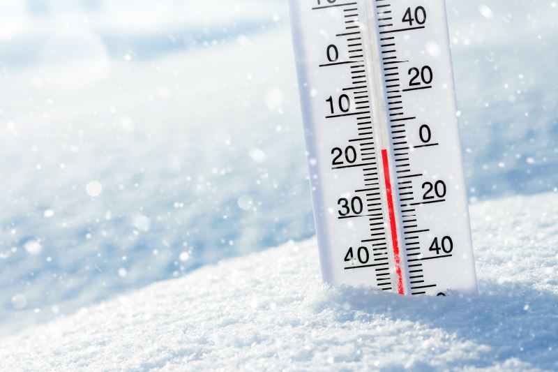 A thermometer, showing a temperature of 0 degrees, sticking out of the snow.
